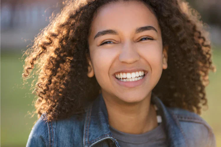 Una adolescente mostrando sus dientes perfectamente alineados.