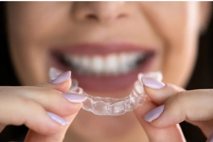 Una mujer aplicándose alineadores transparentes nocturnos.