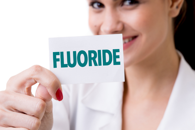 Una doctora sosteniendo una tarjeta flash diciendo fluoruro